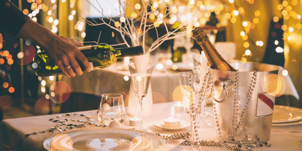 hand pouring wine into a glass on a Christmas party table